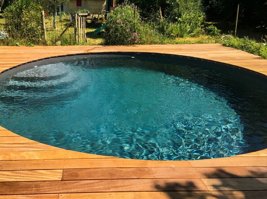 Piscine à débordement extérieure avec margelles en pierre naturelle et parement en moellons dorés, située sur terrain paysager face à la mer