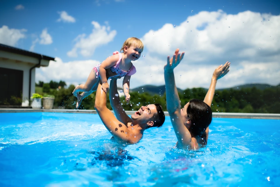 Piscine extérieure avec eau cristalline, entretien en cours par épuisette bleue à manche télescopique capturant débris et feuilles mortes